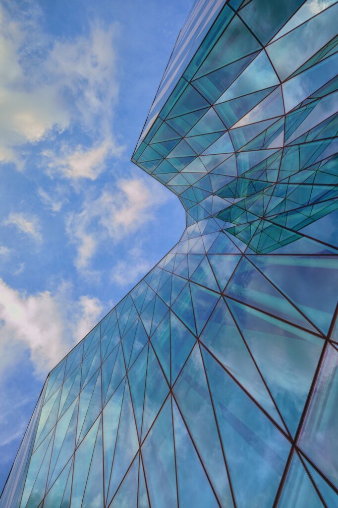 Low angle shot of an urban glass exterior building with transparent windows under a blue sky